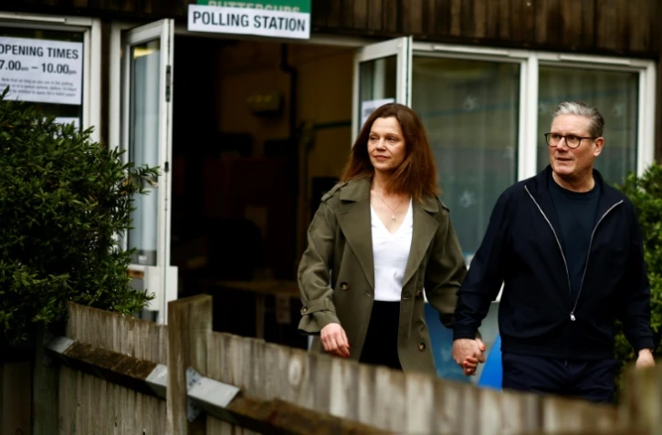 Keir Starmer, le principal chef du parti travailliste d'opposition britannique, et son épouse Victoria Starmer quittent un bureau de vote à Londres, après avoir voté pour les élections locales, le 2 mai 2024