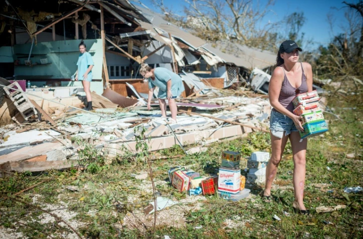 Une famille récupère des marchandises dans une boutique détruite leur appartenant, à Panama City le 11 octobre 2018. 
