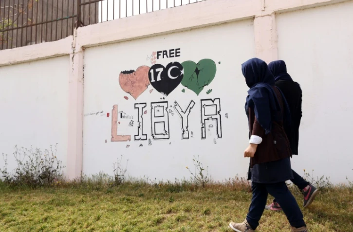 Des étudiants passent à côté d'un graffiti "Libye libre", à Tripoli, le 31 mars 2016
