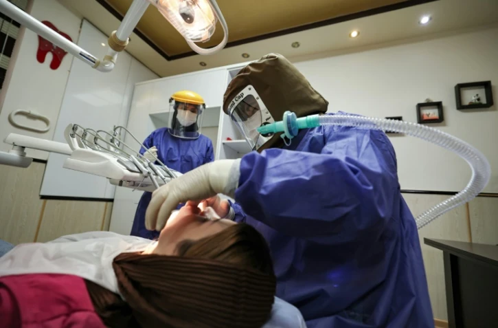 Des stomatologues iraniens portents des costmes de protection contre le Covid-19 dans leur cabinet à Téhéran, le 26 avril 2021.