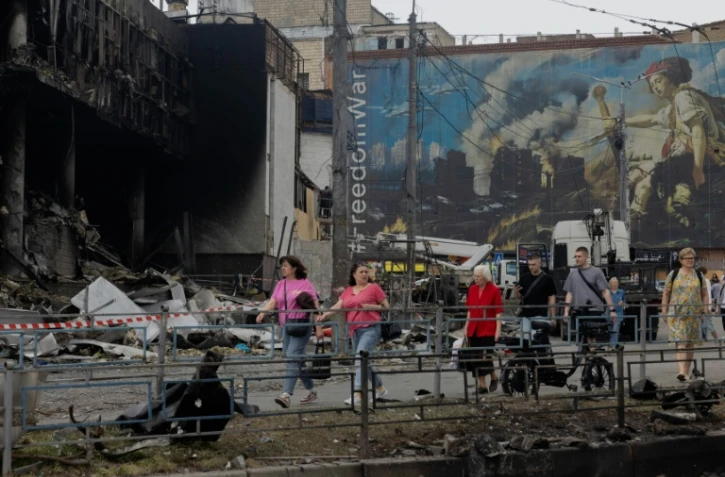 Des habitants passent devant un centre commercial endommagé à la suite des frappes russes à Kiev, le 25 mai 2026