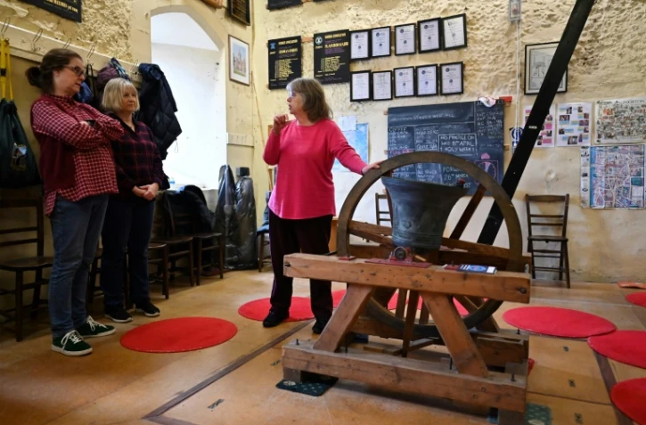 Kate Flavell (d), secrétaire des sonneurs de cloches de l'église de Tous-les-Saints, explique à Charlotte Mafi (2e g) et Anne Porter (2e d) les règles de sécurité, le 25 mars 2023 à Kinston-upon-Thames, près de Londres