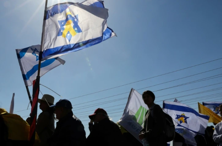 Des Israéliens attendant le passage du convoi funéraire de la famille Bibas, dans le kibboutz Nir Oz le 26 février 2025