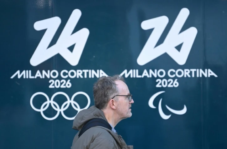 Une personne passe devant les logos des Jeux olympiques et paralympiques d'hiver de Milan Cortina, à Milan, le 5 février 2026