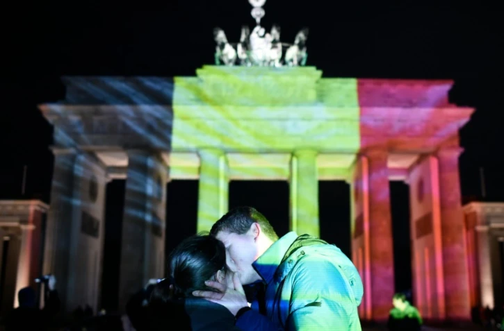 Un couple s'embrasse devant la porte de Brandebourg à Berlin, illuminée aux couleurs de la Belgique, en hommage aux victimes des attentats de Bruxelles