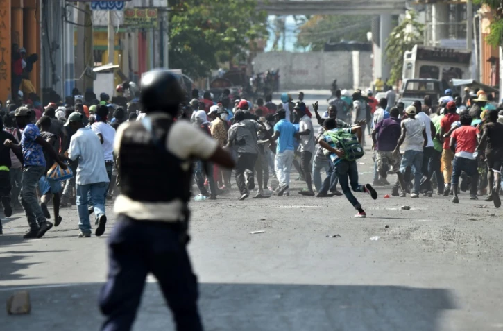 Un policier vise des manifestants avec une arme, lors de violents affrontements à Port-au-Prince, le 13 février 2019 en Haïti