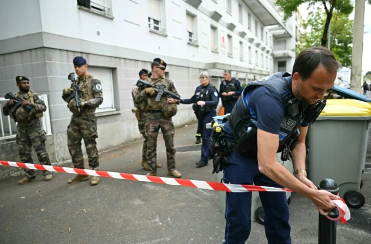 Un policier municipal installe un ruban de police alors que des militaires de l'opération "Sentinelle" sont présents devant le lycée de Nantes où une lycéenne a été tuée et trois autres blessés à coups de couteau par un élève, le 24 avril 2025 