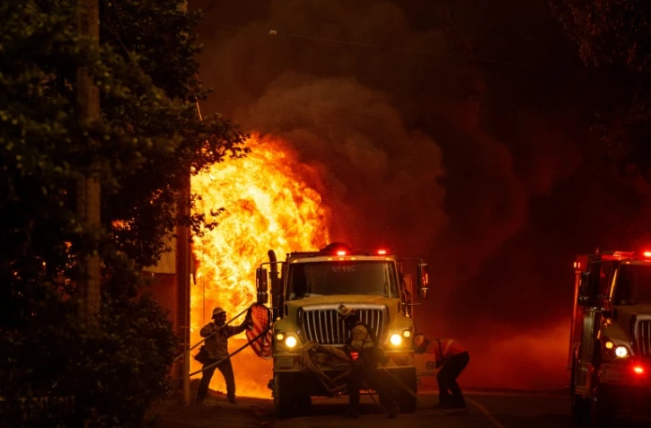 Un pompier sauve un drapeau américain des flammes qui consument une habitation de Greenville, en Californie, le 4 août 2021