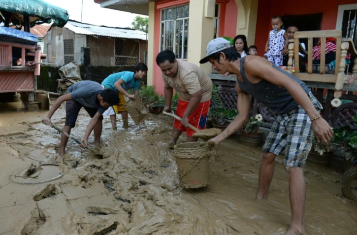 Les habitants enlèvent la boue le 20 octobre 2015 dans les rues de Cabanatuan City, au nord de Manille, apportée par les fortes pluies occasionnées par le typhon Koppu qui a fait au moins 22 morts