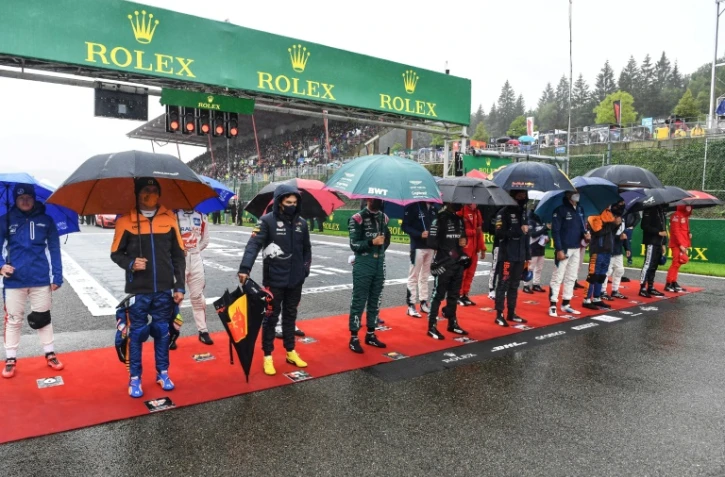Des pilotes attendent sous la pluie sur la ligne de départ du GP de F1 de Belgique menacé par le mauvais temps, le 29 août 2021 à Spa-Francorchamps 