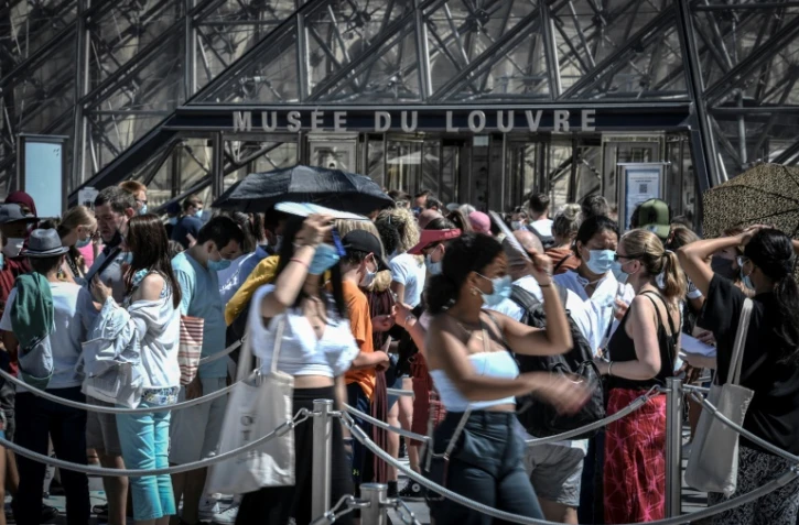 Des visiteurs devant l'entrée du Louvre le 6 août 2020 à Paris