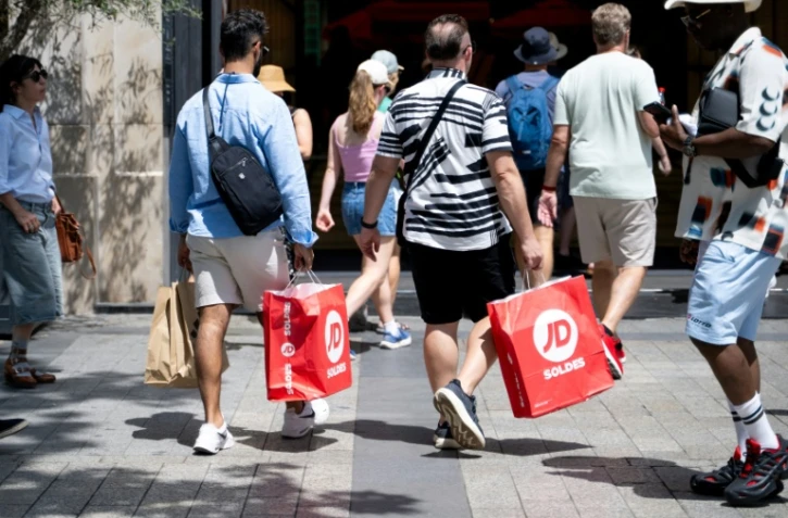 Des passants portent des sacs de courses à Paris, le 25 juin 2025, premier jour des soldes d'été en France