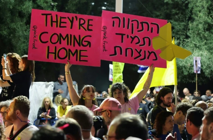 Des femmes brandissent des pancartes lors d’un rassemblement sur la place des Otages à Tel-Aviv, en Israël, avant la libération prévue de dizaines d'otages retenus dans la bande de Gaza, le 11 octobre 2025