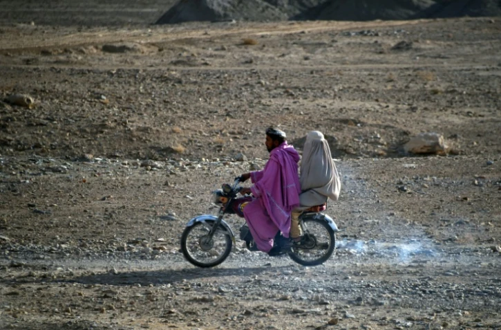 Une femme en burqa assise derrière un homme en moto dans le district d?Arghandab, dans le sud de l?Afghanistan, le 22 février 2021