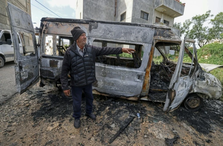Un Palestinien à proximité d'un véhicule calciné après une attaque attribuée à des colons israéliens à Jalud, près de Naplouse, en Cisjordanie occupée, le 22 mars 2026