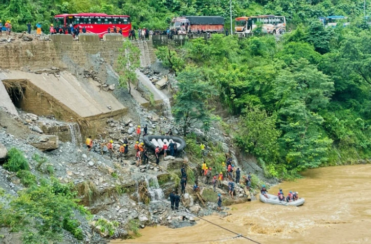 Des équipes de secours recherchent des survivants dans la rivière Trishuli après un glissement de terrain qui a emporté deux bus, le 12 juillet 2024 à Simaltar, au Népal