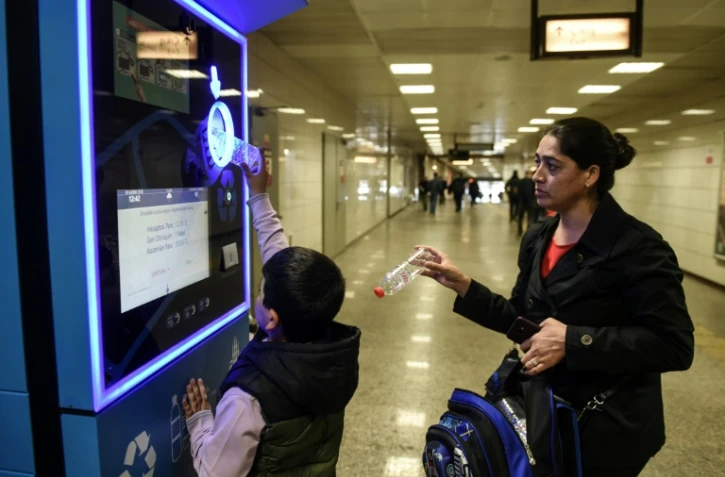 Un enfant turc et sa mÚre recyclent des bouteilles en plastique pour créditer leur carte de transport à Istanbul, le 9 novembre 2018