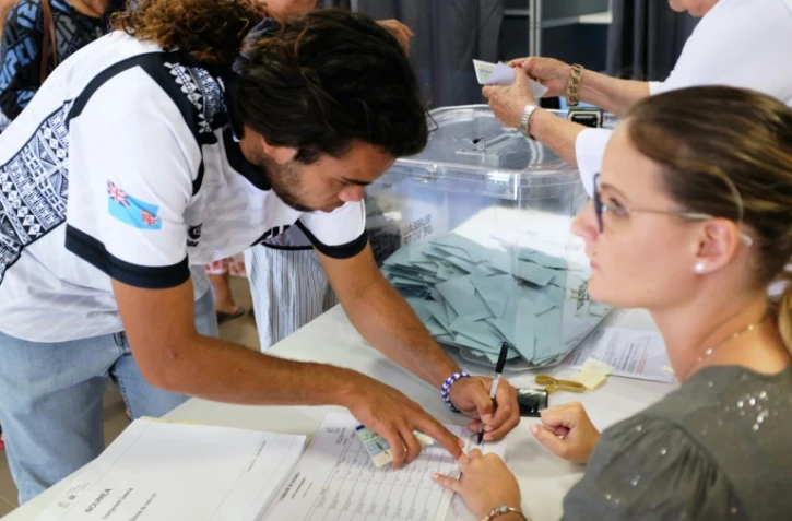 Signature du registre après le vote dans un bureau de Nouméa, le 4 octobre 2020 où se rendent les électeurs pour décider de l'indépendance ou non de la Nouvelle-Calédonie