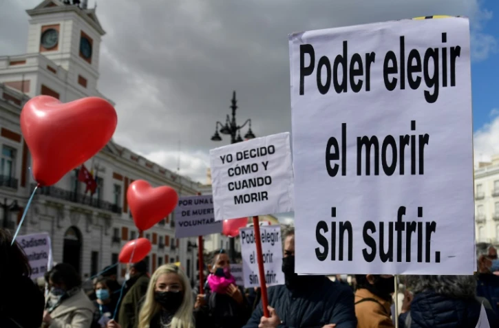 Des personnes tiennent des pancartes sur lesquelles on peut lire "Pouvoir choisir de mourir sans souffrir" et "Je décide quand et comment mourir", lors d'une manifestation en faveur d'une loi légalisant l'euthanasie à Madrid, le 18 mars 2021