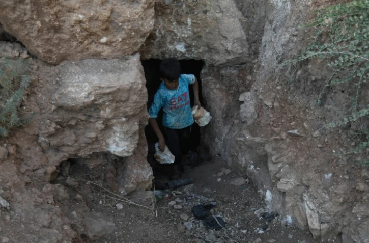 Un enfant transporte des pierres durant des travaux de construction d'un abri souterrain, dans la province syrienne d'Idleb, le 15 septembre 2018