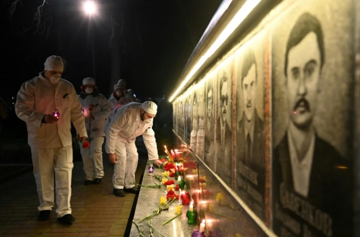 Des employés de la centrale de Tchernobyl allument des bougies et déposent des fleurs devant le monument à la mémoire des victimes de la catastrophe, à Slavutych, la ville où le personnel du site vivait, à 50 km du site, le 25 avril 2021