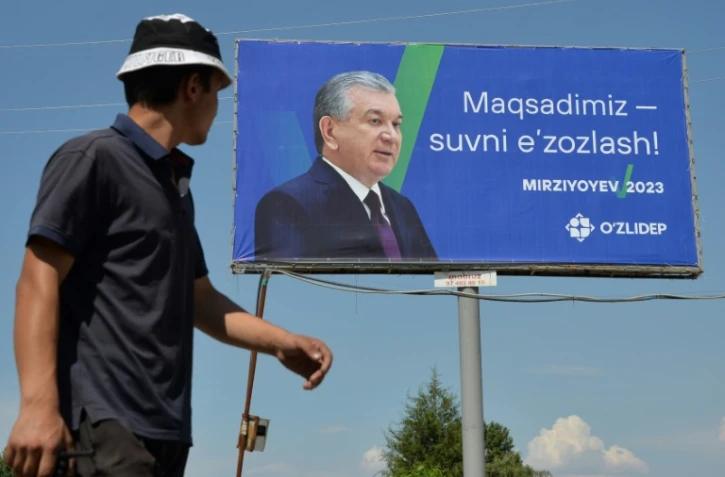 Un homme passe à côté d'une affiche de campagne du président de l'Ouzbékistan Chavkat Mirzioïev, à la veille d'un scrutin anticipé, non loin de la capitale Tachkent, le 8 juillet 2023