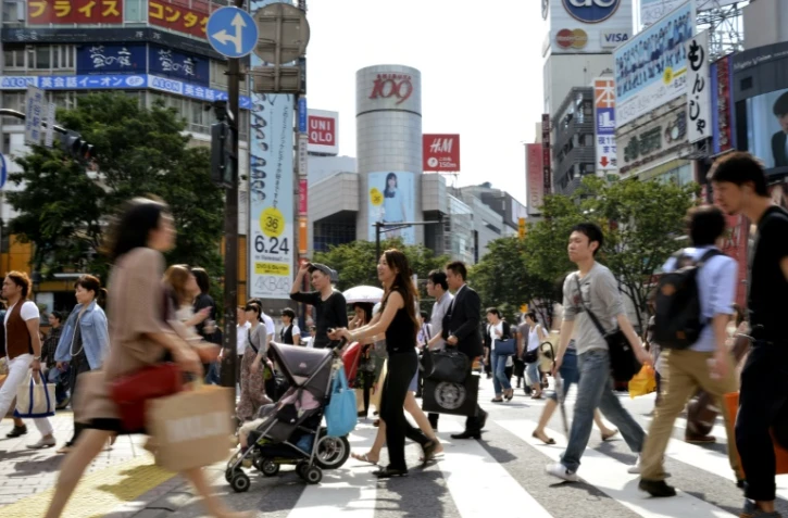 Des piétons traversent une rue devant la station de métro de Shibuya à Tokyo, le 21 juin 2011