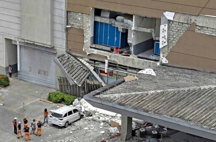 Les autorités inspectent un mur endommagé à l'extérieur d'un centre commercial à Butuan, sur l'île méridionale de Mindanao, le 10 octobre 2025, après un séisme qui a frappé le sud des Philippines