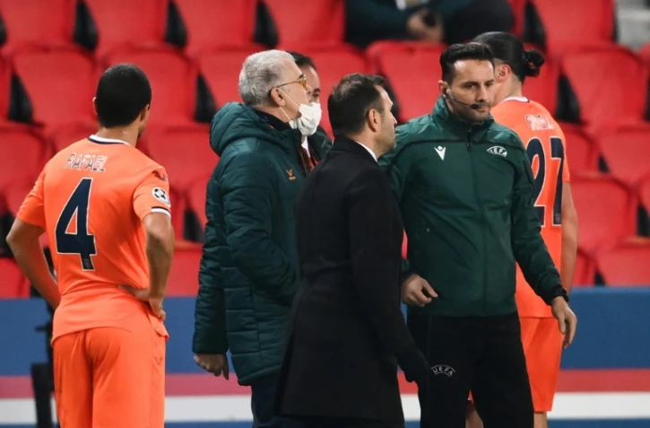 L'entraîneur de l'Istanbul Basaksehir, Okan Buruk (g), discute avec le 4e arbitre roumain Sebastian Coltescu (d) après l'interruption du match de groupes de la Ligue des champions contre le Paris-SG, au Parc des Princes, le 8 décembre 2020