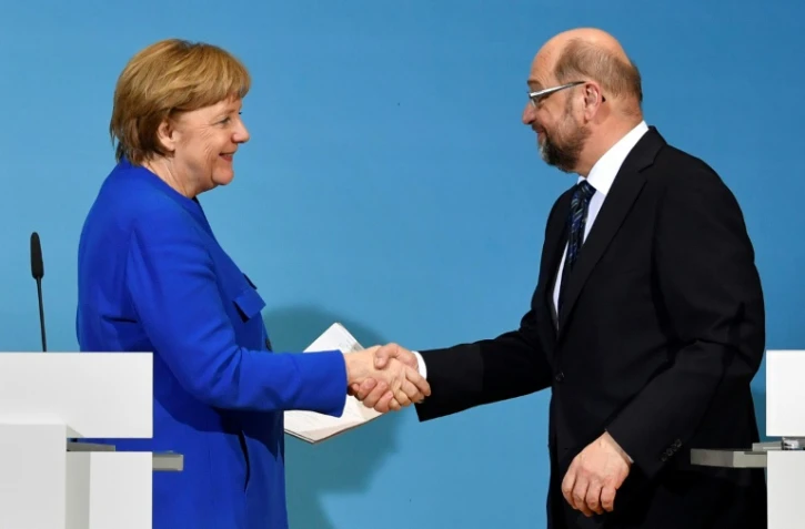 La chancelière allemande Angela Merkel serre la main du socio-démocrate Martin Schulz, après une conférence de presse commune à Berlin, le 12 janvier 2018