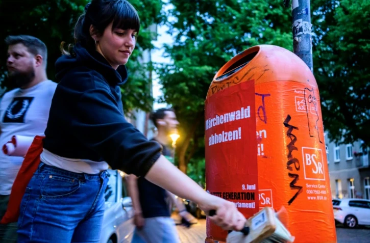 Des membres du mouvement écologiste Letzte Generation, dont la candidate Carla Hinrichs (c), collent des affiches de campagne pour les européennes, le 21 mai 2024 à Berlin