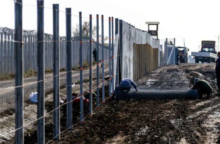 Des détenus érigent une clôture à la frontière hongro-serbe dans le village de Gara, le 27 octobre 2016, destinée à empêcher des migrants d'entrer en Hongrie