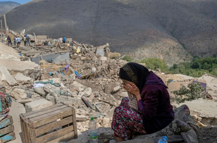 Photo prise le 12 septembre 2023 dans le village de Imi N'Talat, dans le centre du Maroc, montrant une femme pleurant devant les décombres d'une maison après un puissant séisme