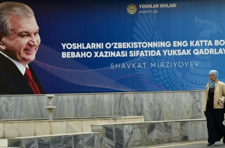 Une femme passe le 20 octobre 2021 à Tachkent devant une affiche de campagne du président de l'Ouzbékistan Chavkat Mirzioïev, réélu dimanche