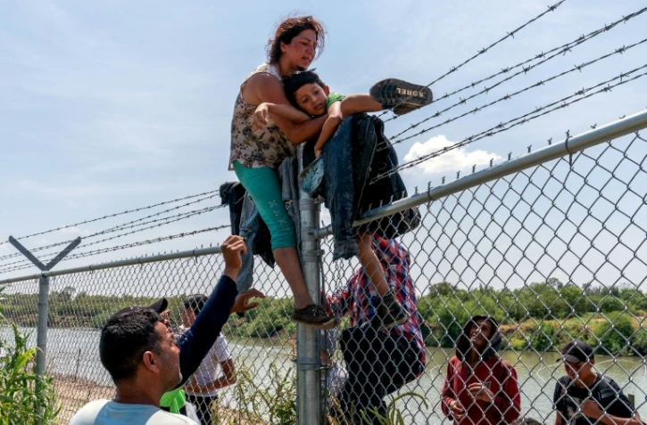 Nataly Barrionuevo, son fils dans les bras, escalade une clôture de barbelés après avoir traversé le Rio Grande du côté mexicain et être entré aux Etats-Unis à Eagle Pass, au Texas, le 25 août 2023
