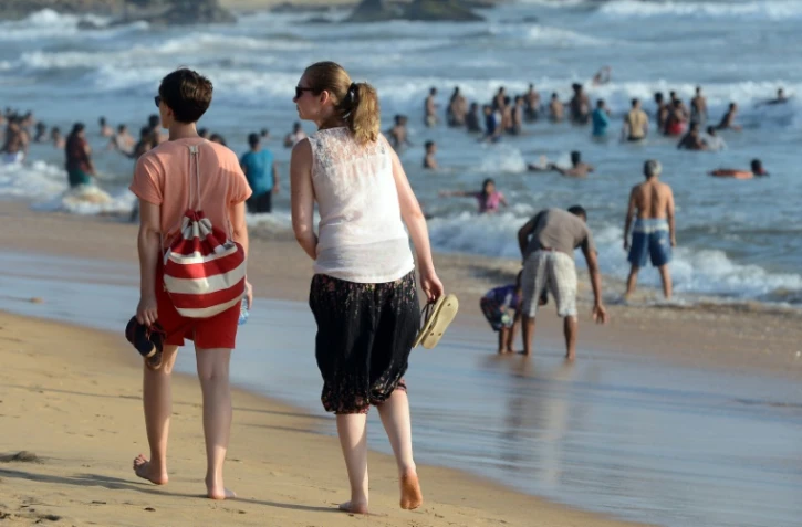 Des touristes se promènent sur la plage de Mount Lavinia, sud de Colombo, le 3 juillet 2016