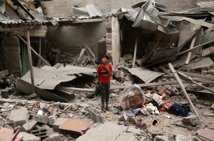 Un enfant palestinien se tient parmi les débris d'une maison détruite par un bombardement israélien à Rafah, dans le sud de la bande de Gaza, le 27 avril 2024
