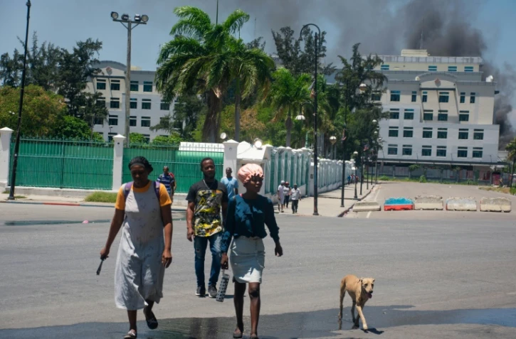 De la fumée s'échappe d'un bâtiment du ministère des Finances, alors que des habitants quittent les lieux après avoir entendu des tirs, le 2 avril 2024 à Port-au-Prince, en Haïti