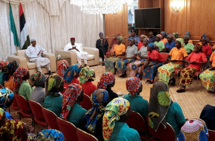Une photo diffusée par PGDBA&HND Mass Communication montre le président nigérian Muhammadu Buhari (g) qui accueille 82 lycéennes de Chibok libérées à Abuja, le 7 mai 2017