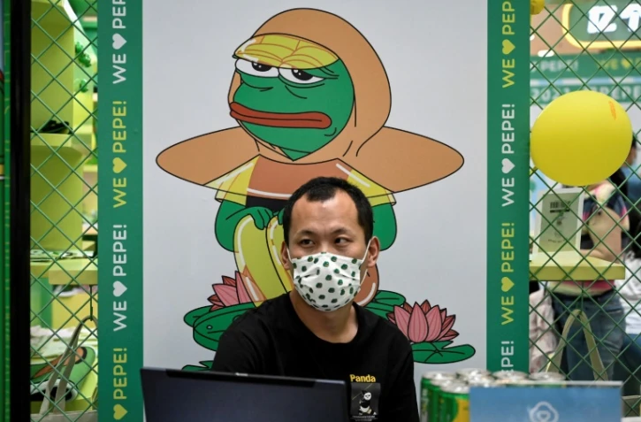 Un homme est assis devant une affiche de Pepe the Frog, symbole de la désillusion de la jeunesse chinoise, dans un centre commercial de Pékin, le 29 mai 2021