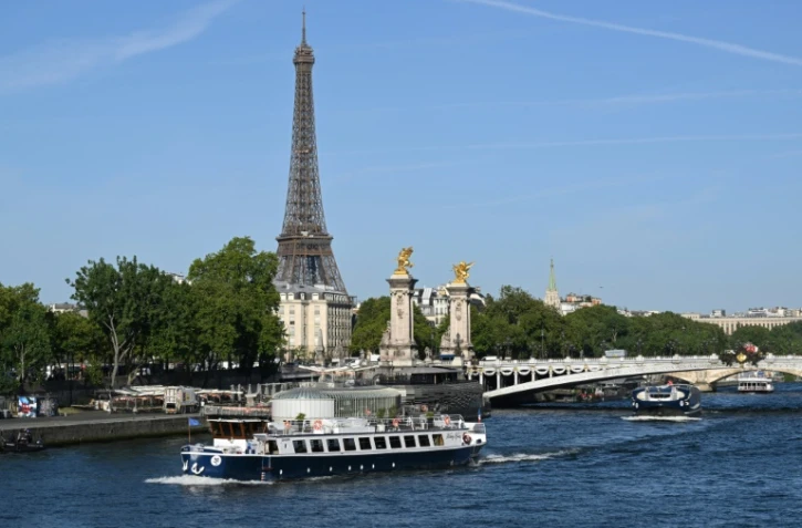 Une péniche passe devant la Tour Eiffel, sur la Seine, le 17 juillet 2023, lors d'un test des "manœuvres", "distances", "durée" et "capture vidéo" de la future cérémonie d'ouverture des JO de Paris en 2024