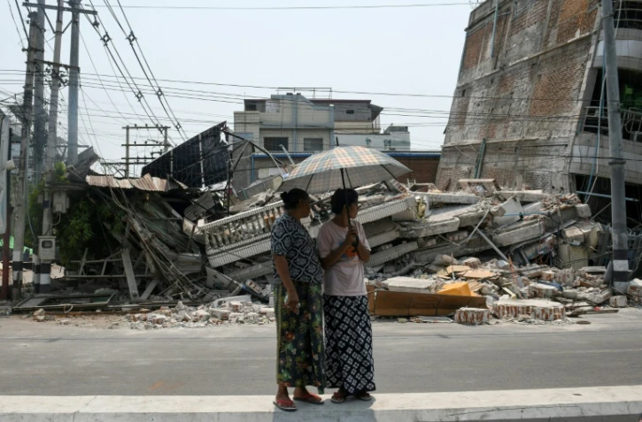 Des personnes se tiennent à côté d'un bâtiment endommagé à Mandalay, en Birmanie, le 30 mars 2025