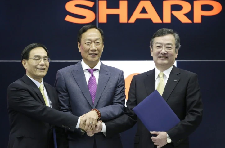 Le président de Hon Hai Precision, connu aussi sous le nom de Foxconn, Terry Guo (C) et le vice-président Tai Jeng-wu (G) posent avec le président de Sharp Kozo Takahashi (D), lors d'une conférence de presse à Osaka le 2 avril 2016