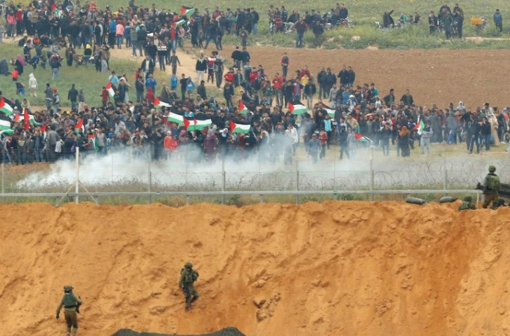 Des manifestants palestiniens et des soldats israéliens se font face à la frontière de la bande de Gaza, le 30 mars 2018