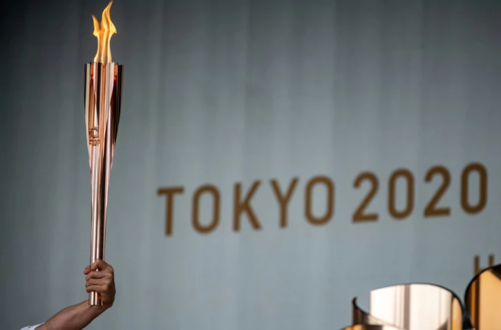 Un relayeur tient le flambeau olympique lors de la cérémonie d&rsquo;allumage de la flamme olympique au premier jour du relais à Machida, à l'ouest de Tokyo, le 9 juillet 2021