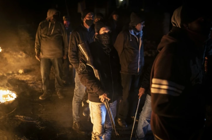 Des riverains organisés en groupe de protection contre les pillards, armés de fusils et de machettes, à un poste de contrôle à l'entrée du township de Phoenix, à Durban, en Afrique du Sud, le 15 juillet 2021.