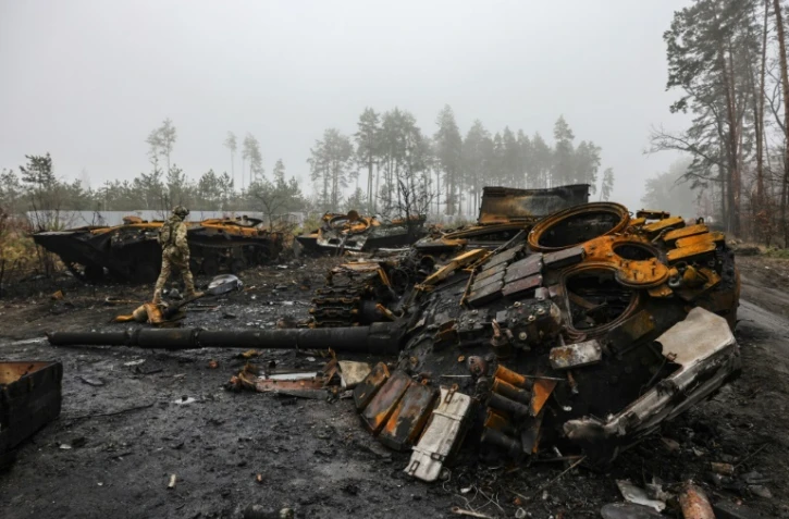 Un soldat ukrainien passe à côté d'un tank russe détruit, dans les faubourgs de Kiev, le 1er avril 2022