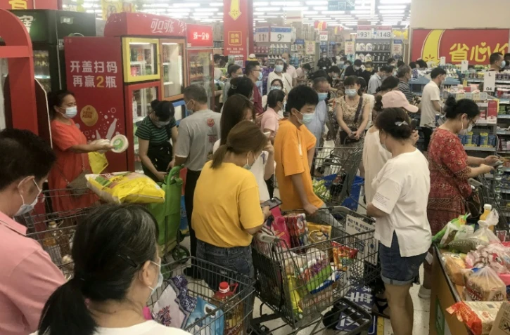 Das habitants de la ville chinoise de Wuhan font des achats dans un supermarché le 2 août 2021 