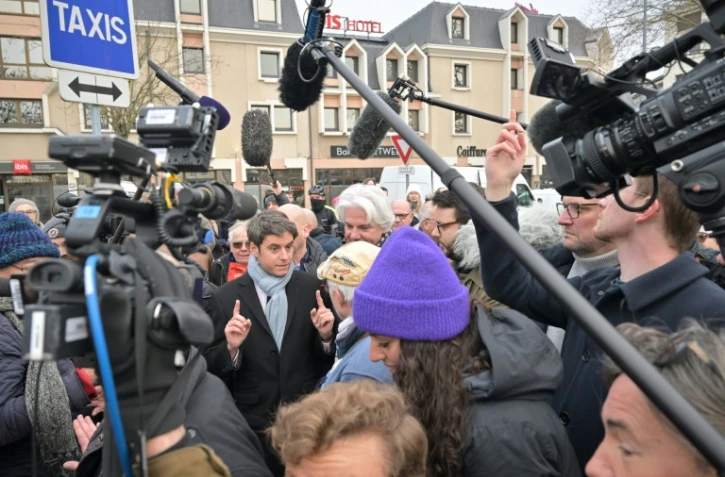 Le Premier ministre Gabriel Attal (c) parle avec des habitants sur le marché de Caen, le 14 janvier 2024 dans le Calvados