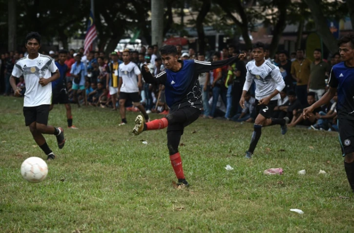 Un Rohingya de l'équipe Cheras Harimau frappe la balle tandis que des joueurs de Selangor (en blanc) le regardent lors d'un tournoi destiné aux réfugiés, à l'occasion des célébrations de la fin du ramadan en Malaisie, à Kuala Lumpur, le 18 juin 2018